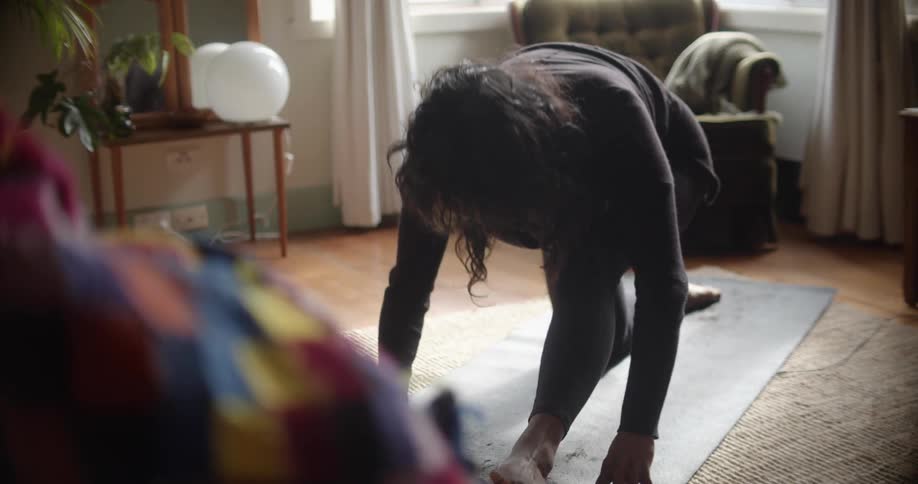 A woman kneels on a yoga mat and stretches upward in a yoga pose