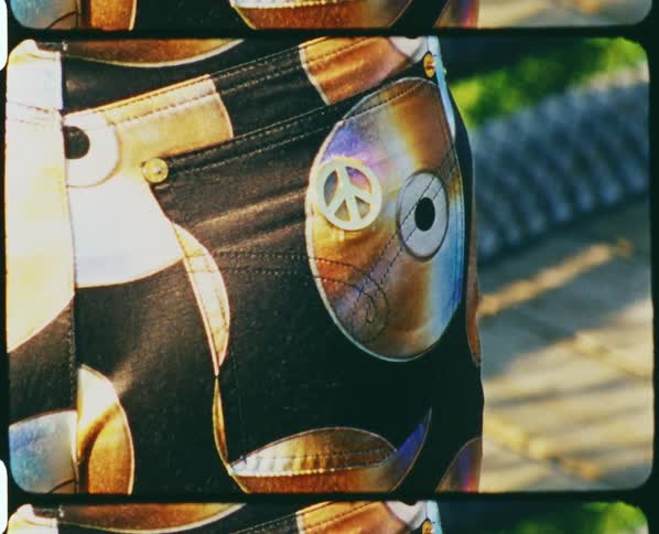 A woman wearing pants with cds and a peace symbol outside