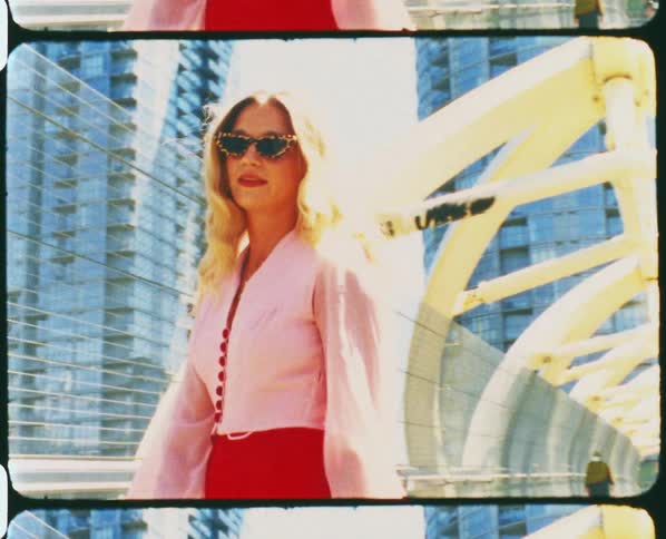 A woman in fashionable clothing paces back and forth on a bridge in a metropolis during the day