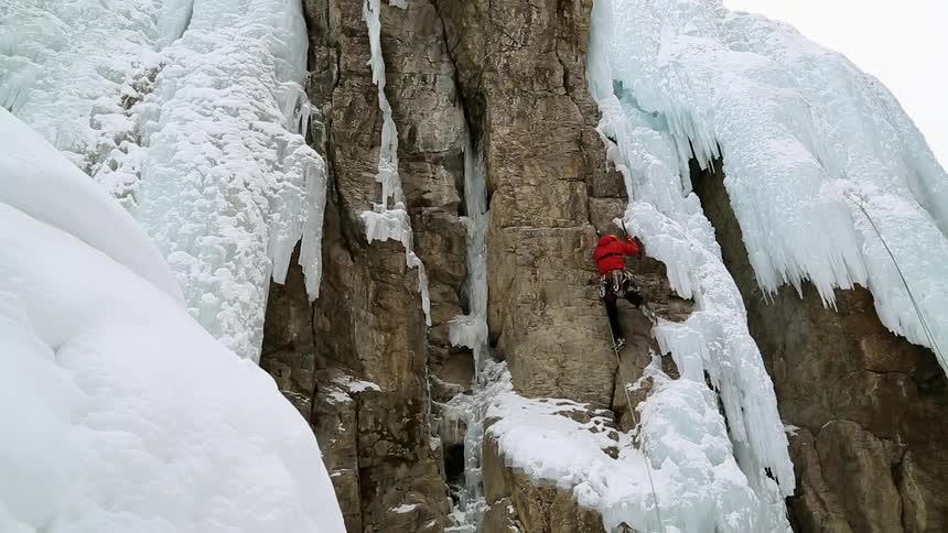 A person in red climbs a rock face