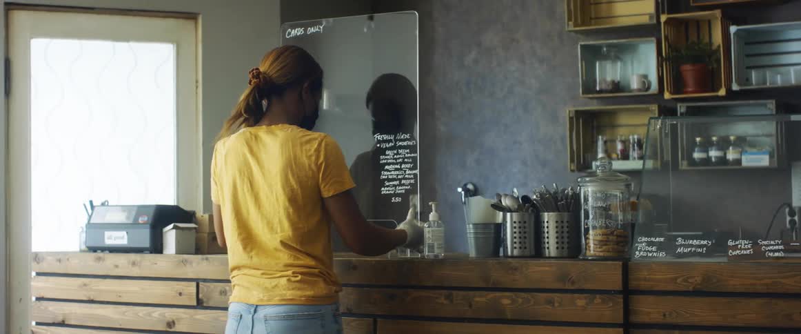 A woman cleaning and moving a sign in a business