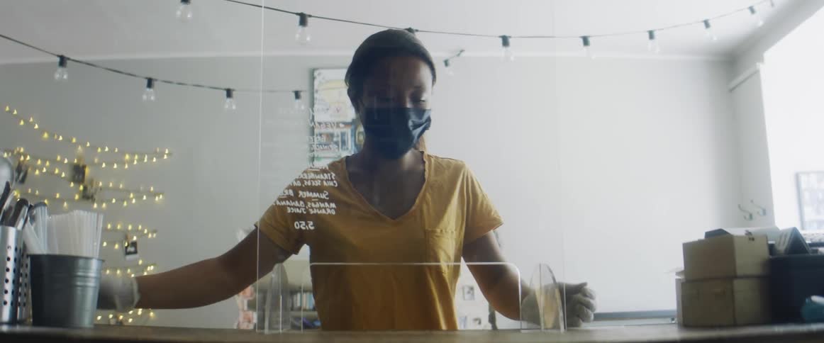 A woman with a mask and gloves placing a glass display on a counter