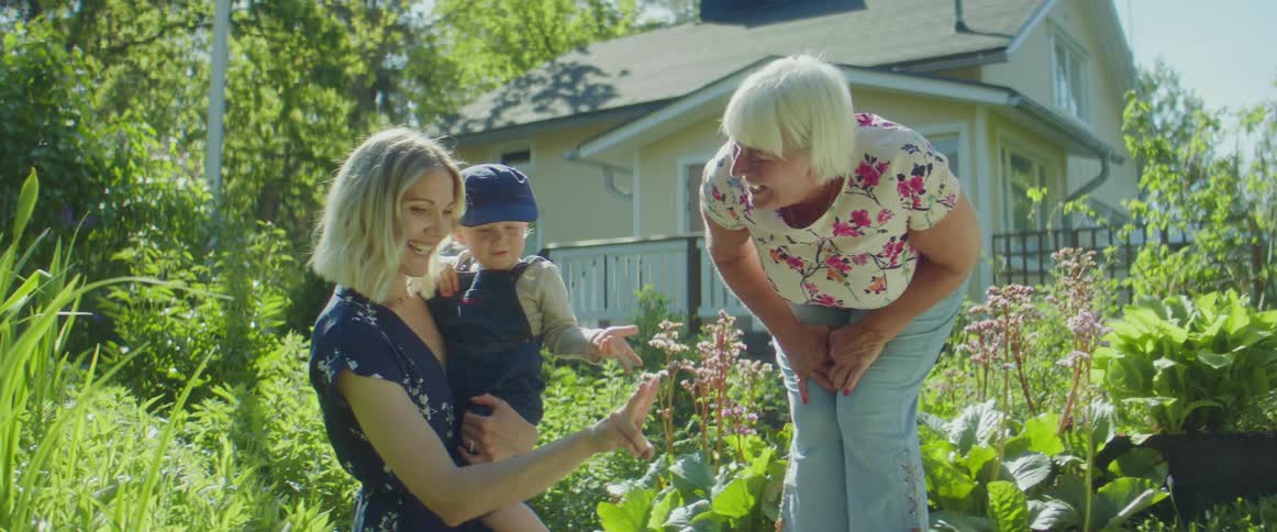 A woman holds a toddler boy outside standing next to her own mother