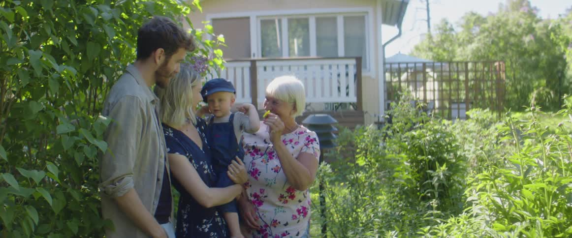 Family of four standing among the greens in the garden on the backyard of a house