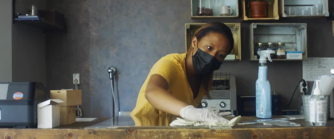 An employee cleans the countertops of a restaurant order table