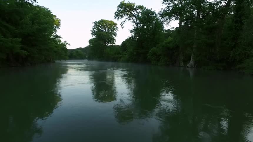 A tree lined river on a cloudy day