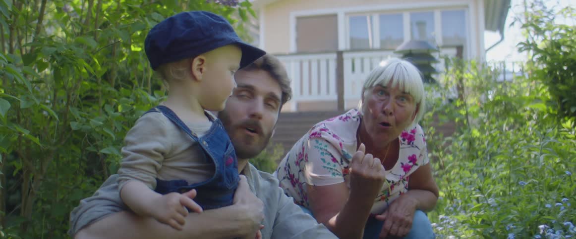 Father and son sharing a moment with grandma on the garden in the backyard
