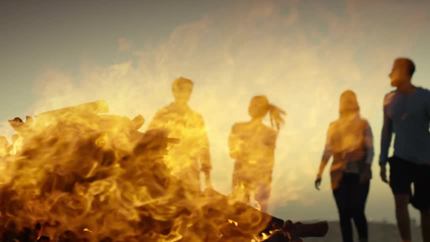 A group of people walk towards a large bonfire
