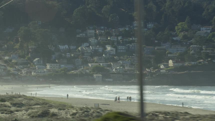 Waves are crashing on a beach near a city