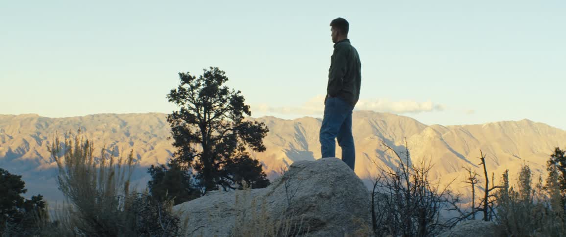 A man stands in a canyon with his hands in his pockets