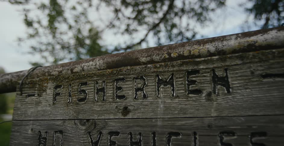 A wooden sign on a metal rail declares fisherman no vehicles