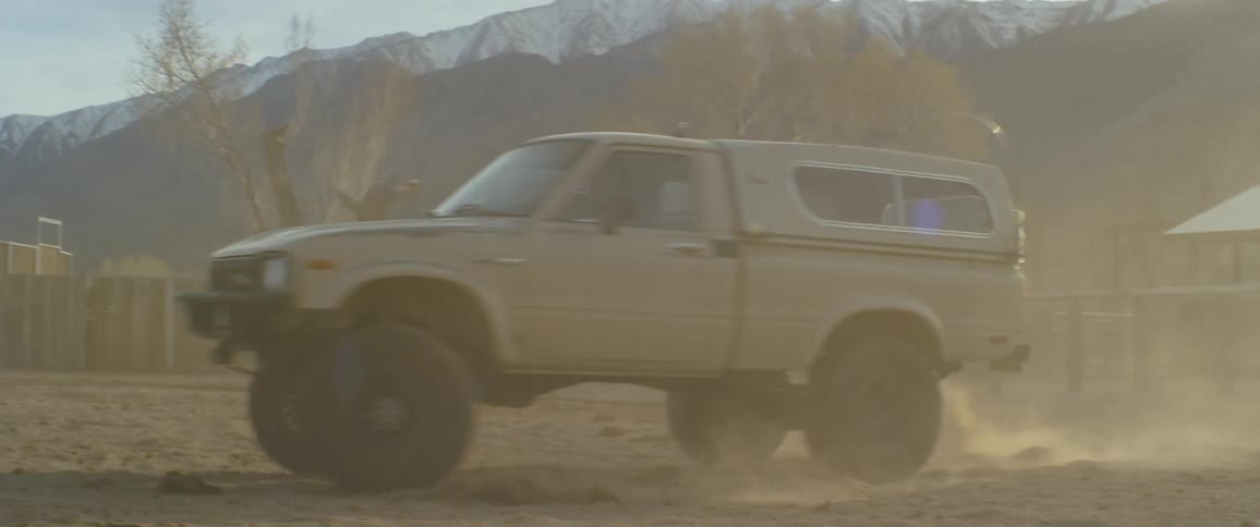 A truck races around a dirt area kicking up a lot of dust