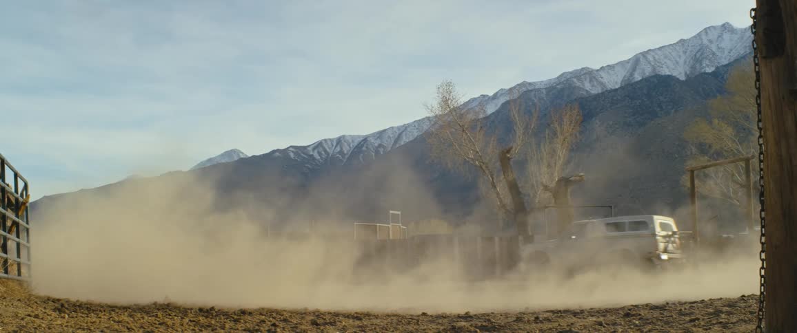 A truck kicks up dirt as it drives in a circle near a canyon