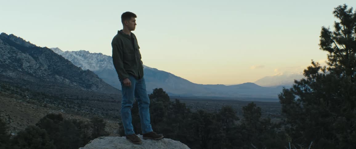 A man enjoying a mountain view while hiking at sunset