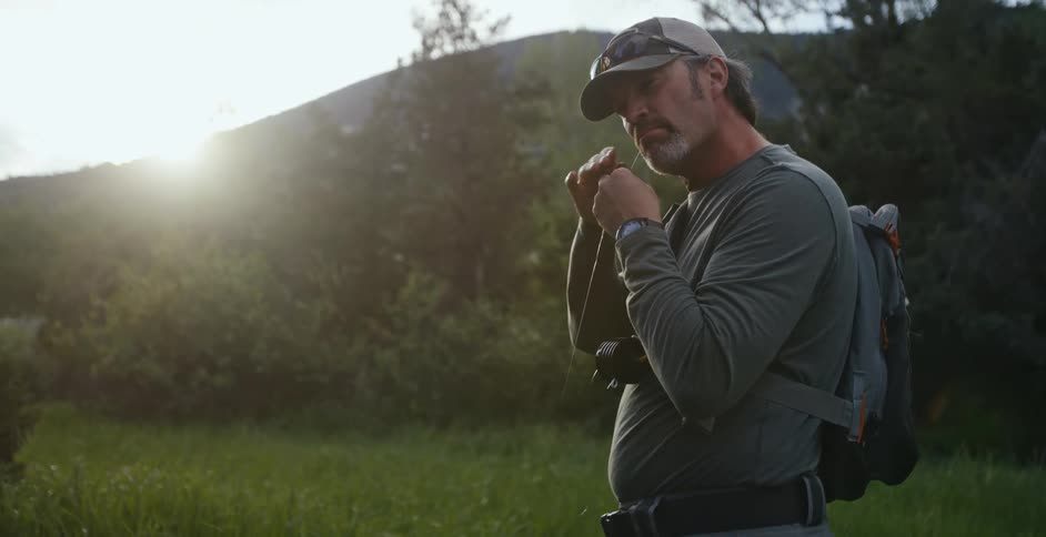 A man taking out headphones while hiking