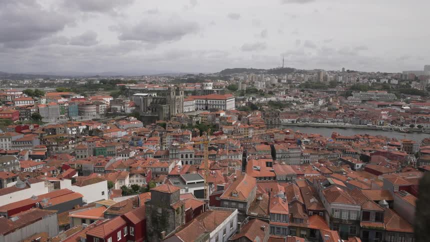 A river runs through a dense city filled with buildings with terracotta roofs