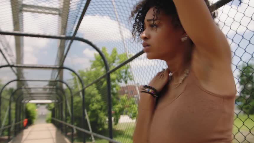 A woman dances on an overpass as traffic passes by under her