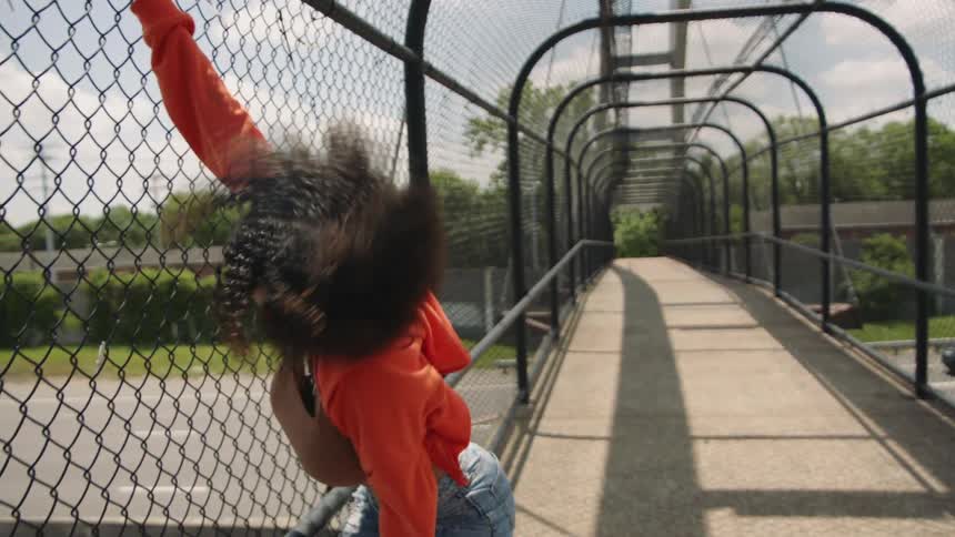 A woman dancing outdoors on a bridge