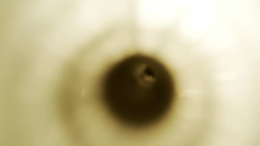 Dark sediment gathers at the bottom of a centrifuge as it spins faster and faster