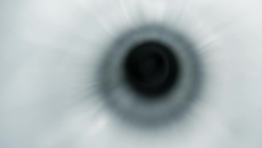 An extreme closeup shows liquid flowing and rippling as it enters a small hole