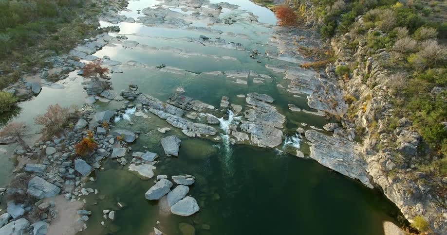 Aerial view moving down a river with large rocks