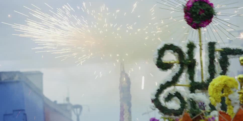 Flower decorated floats and signs bounce up and down beside a spinning sparkler
