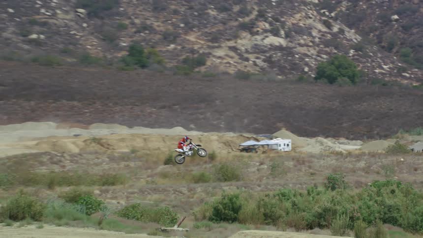 A man riding a dirt bike down a trail with jumps
