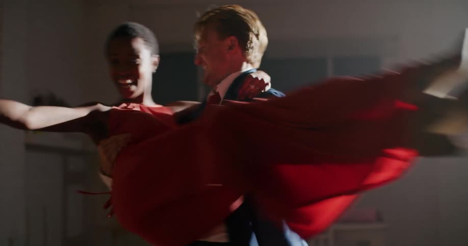 A man and a woman in a room dancing with a wall in the background