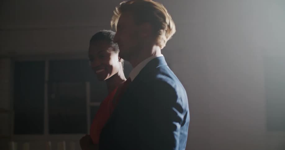 A man and a young woman dance together in a dimly lit room