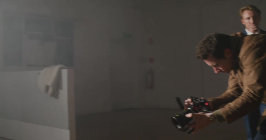 Photographer aims camera low as model poses and another man watches