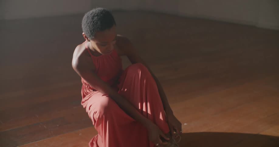 A woman is tying her shoes on the floor