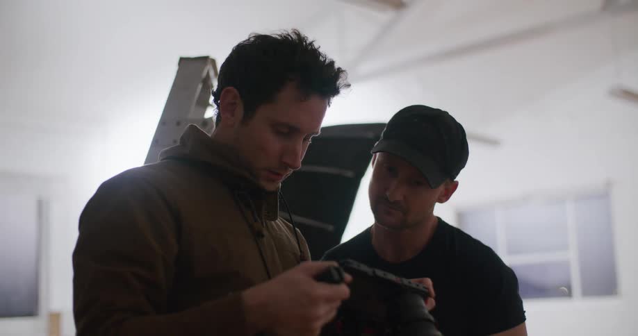 Two men standing in photography studio view contents of digital camera memory