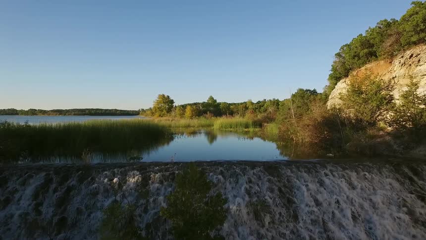A lake with weeds poking out of it and a shoreline