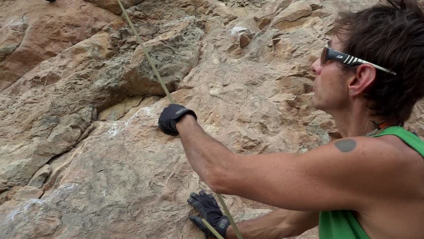 A man is holding a cord on the side of a cliff