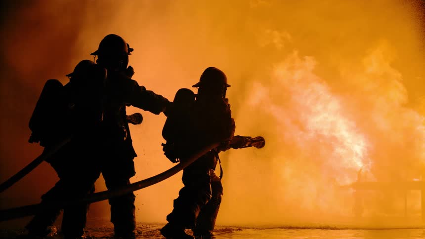 A group of firefighters fighting a fire at night
