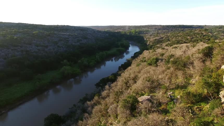A person stands on a balcony overlooking a river
