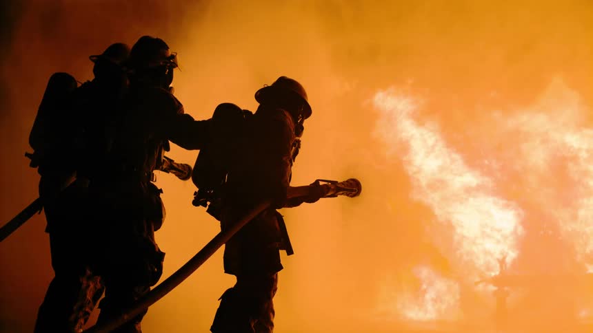 A group of three firemen putting out a fire