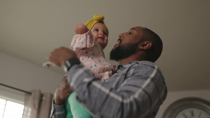 Father holds and kisses daughter in the living room at home