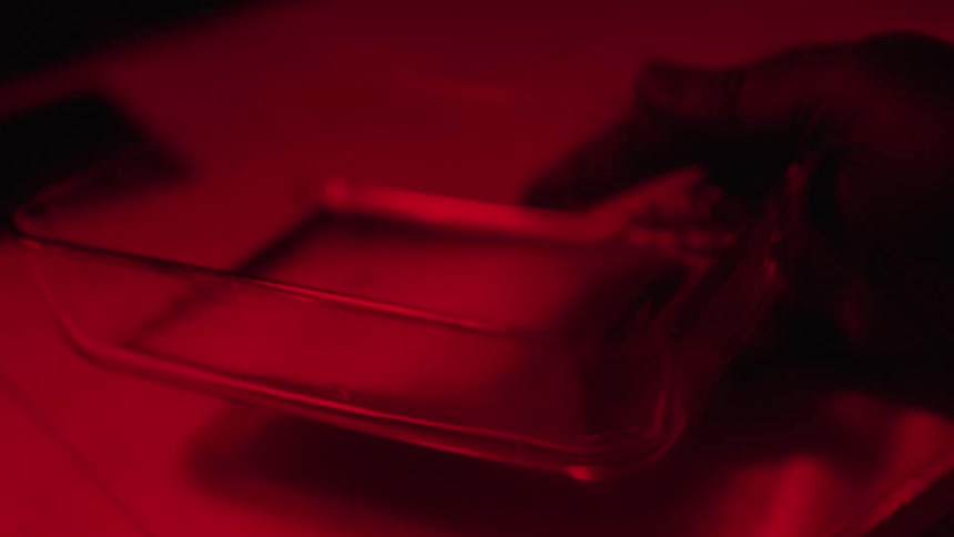 A person in a dark room developing film