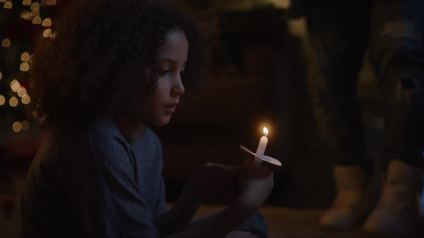 Father lights a vigil candle for her smiling daughter at home at night
