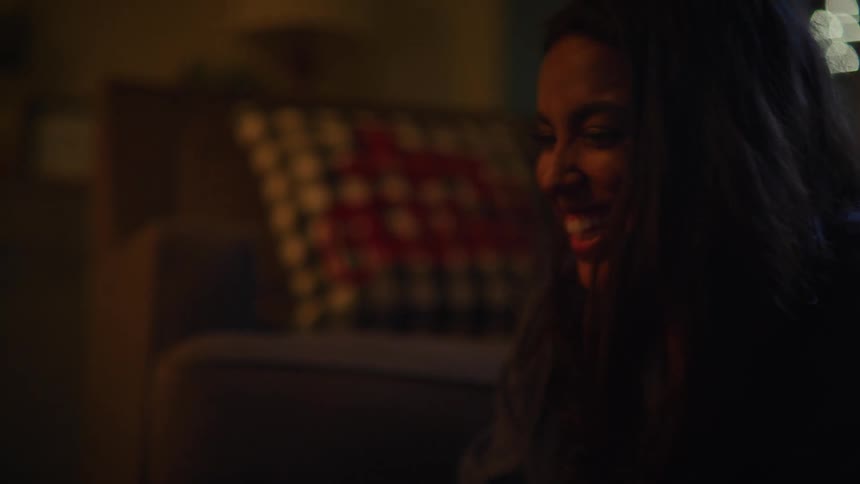 Happy woman lauging and smiling on the floor of the living room at night