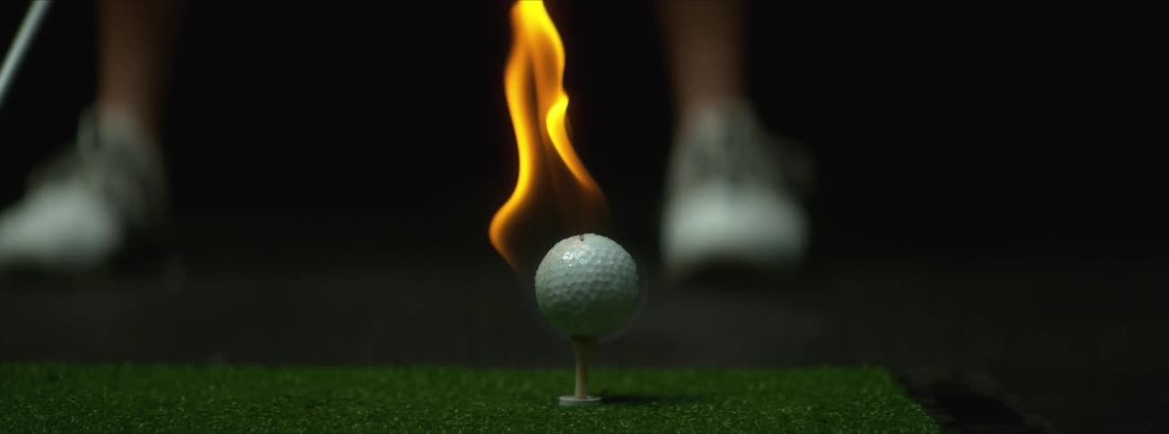 A person is driving a burning golf ball
