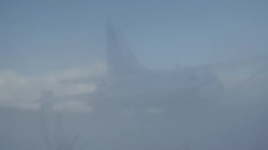 A small airplane takes off blowing dust around