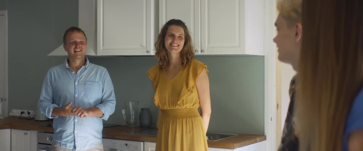 A family is standing and talking in a home kitchen during the day