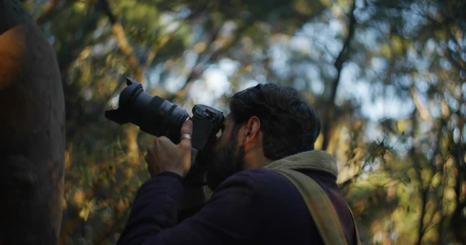 A photographer takes photos with a long lens then looks at the display screen