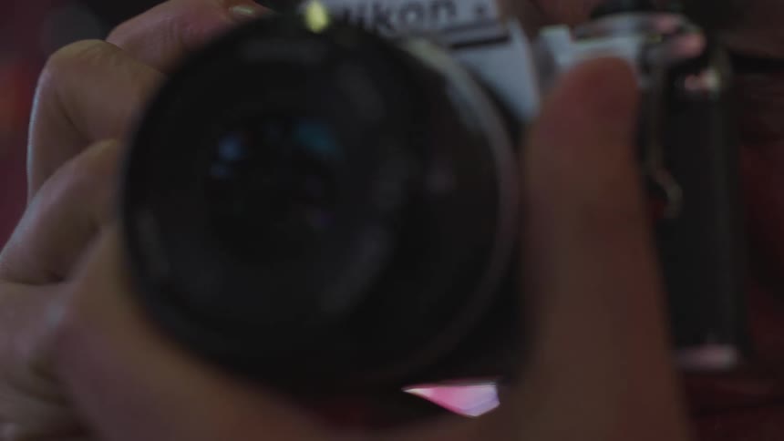 A photographer uses a camera to take a photograph in a city at night
