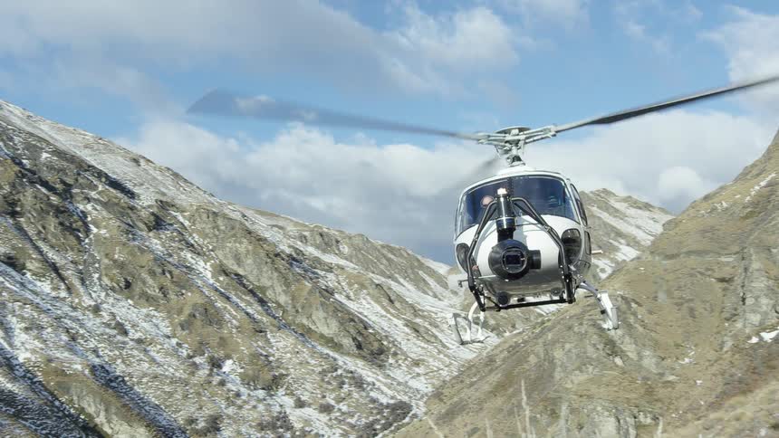 A helicopter is flying near mountains and a road