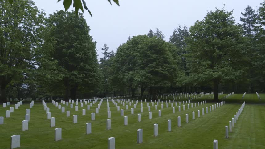 Slow tilt down reveal of a beautiful and somber veterans veterens cemetary on an overcast day