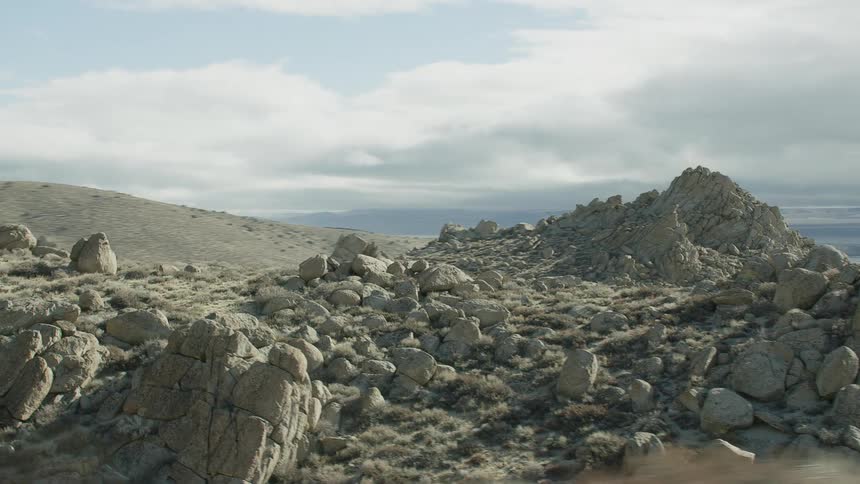 A rocky barren landscape under a blue sky with white clouds