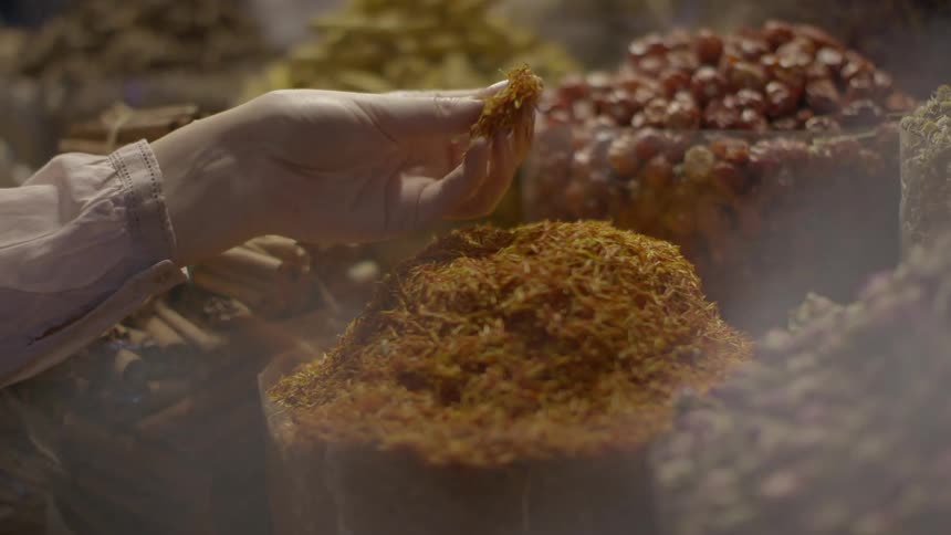 A women bends to breathe in the aroma of the fresh spices and herbs in a market